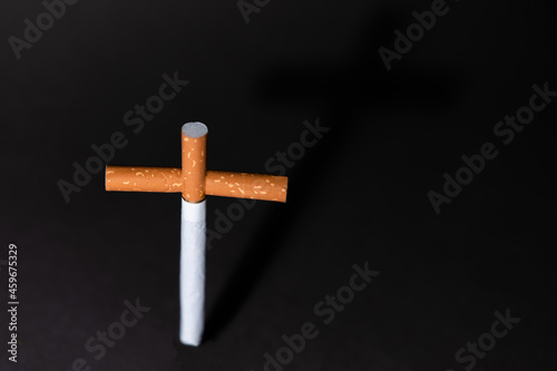 Cross from cigarettes on a black background. Symbol