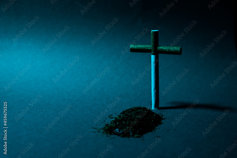 Fototapeta premium Cross from a cigarette against a dark background. Symbol