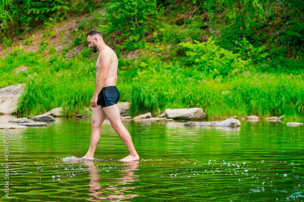 A man walks barefoot on the surface of the water like jesus. The tourist is preparing to sail. The young man enjoys water treatments. The traveler stopped by the river to swim. Copy space A man walks barefoot on the surface of the water like jesus. The tourist is preparing to sail. The young man enjoys water treatments. The traveler stopped by the river to swim. Copy space