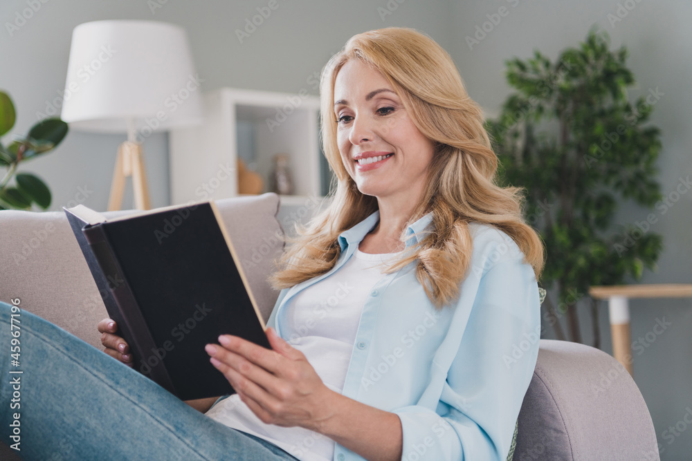 Photo of relaxed cheerful lady toothy shiny smile sit couch read book wear blue shirt home apartment indoors Photo of relaxed cheerful lady toothy shiny smile sit couch read book wear blue shirt home apartment indoors