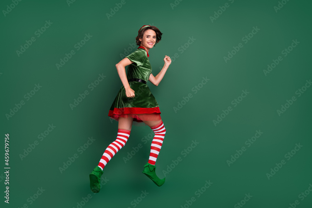 Photo of energetic lady jump hurry wear elf costume hat striped socks isolated green color background