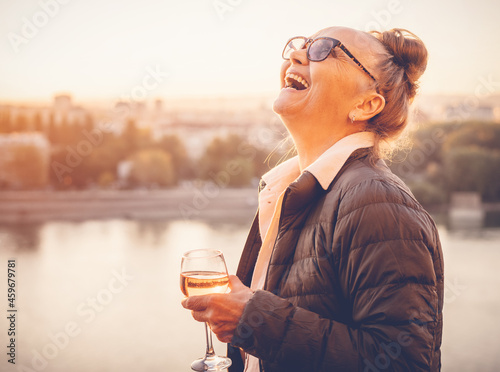 Beautiful happy mature woman enjoying a glass of wine at sunset. Active retirees concept