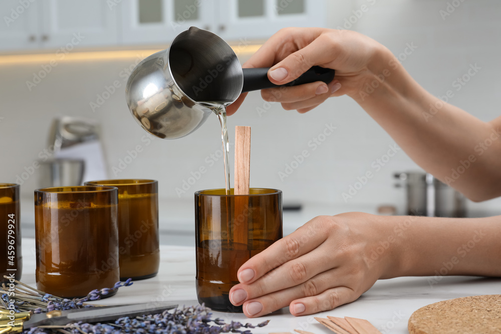 Woman making homemade candle at table in kitchen, closeup - obrazy, fototapety, plakaty 