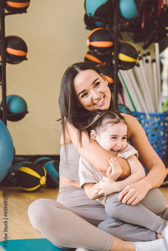 Obraz premium Mom and daughter cuddle. Exercise in the gym with large