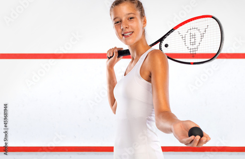 Squash player on a squash court with racket. White sportswear. Beautiful girl teenager and athlete with racket on court. Sport concept. photo