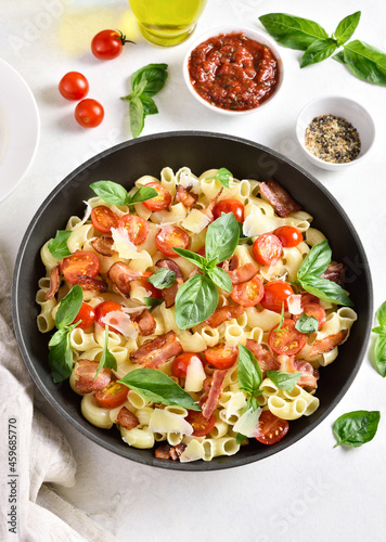 Tomato and bacon pasta with parmesan cheese and basil leaves