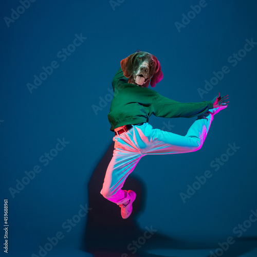 Art collage. Young woman, hip hop dancer headed of dog's head dancing isolated on navy old color background. Sstreet dance style.