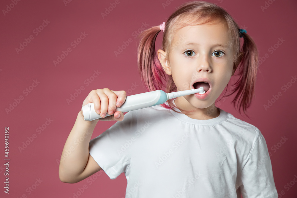 Smiling caucasian little girl cleaning his teeth with electric sonic toothbrush Smiling caucasian little girl cleaning his teeth with electric sonic toothbrush