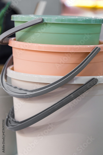 Various plastic new empty buckets stacked. Inventory and household items in trendy pastel colors. Industrial background