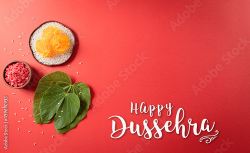 Happy Dussehra. Yellow flowers, green leaf and rice on red background. Dussehra Indian Festival concept. photo