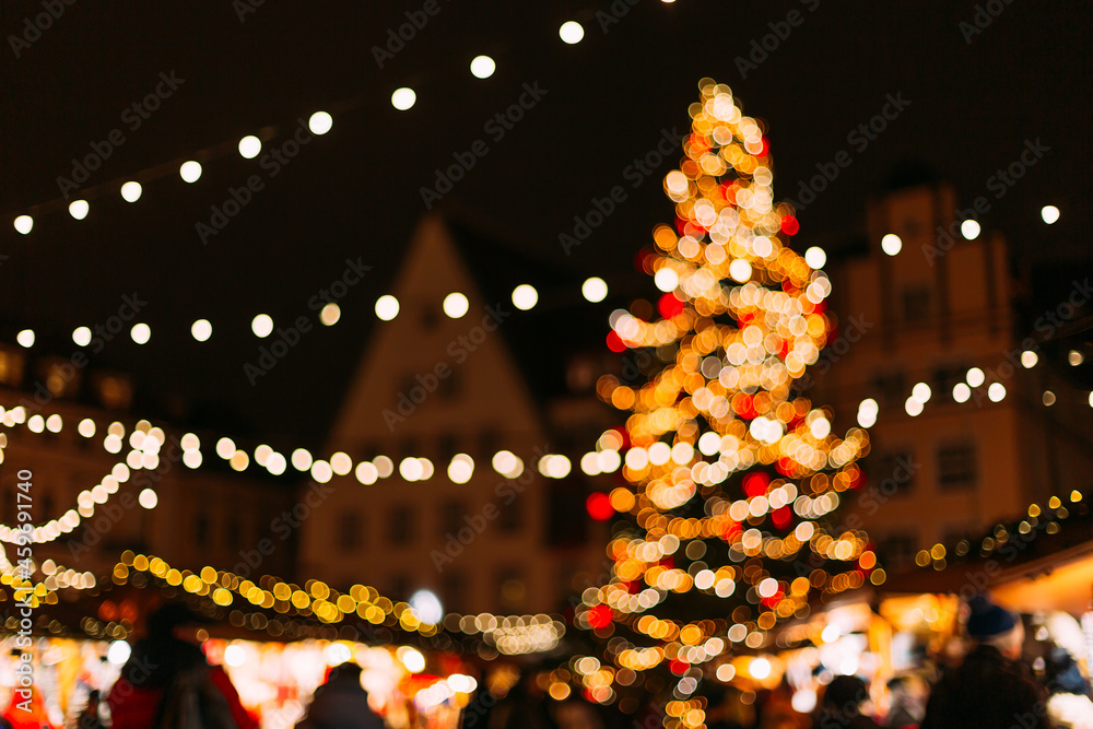 Christmas lights at the Christmas market of the old European city. New Year's garlands at the fair. A festive atmosphere on the main square in the city. The photo was taken out of focus