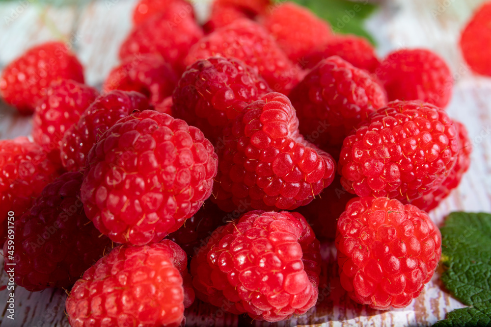 A handful of scarlet ripe raspberries on the old wooden table. A handful of scarlet ripe raspberries on the old wooden table.