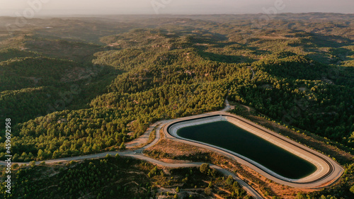 Aerial view of mountaintop reservoir at dusk with forested hills in background photo
