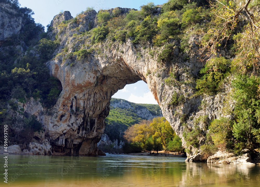 Fototapeta premium Rock Arch Pont D'Arc In The Canyon Of The Gorges De L'Ardeche With Reflections On The River Ardeche In France On A Beautiful Autumn Day With A Clear Blue Sky