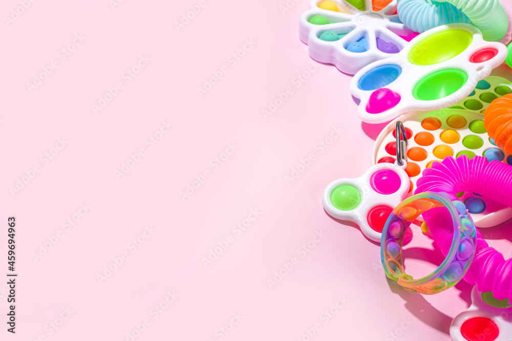 Modern trendy kids fidget finger toys, relaxation concept - set of different bright pop-it, simple-dimple, squishy, pop-tubes, on colorful pink background, top view copy space Modern trendy kids fidget finger toys, relaxation concept - set of different bright pop-it, simple-dimple, squishy, pop-tubes, on colorful pink background, top view copy space