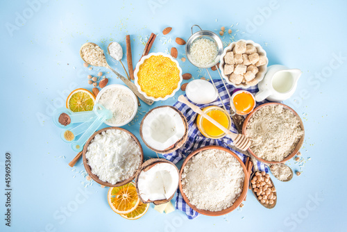 Cooking baking background frame background. Selection of various gluten free flour and ingredients, for sweet and bread bakery, on colorful blue kitchen table with utensils, eggs, sugar, cinnamon