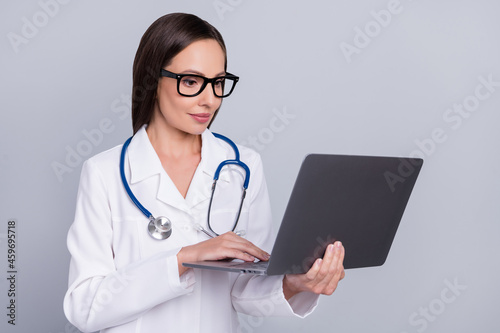 Photo of sweet adorable woman doc dressed white spectacles typing modern device smiling isolated grey color background