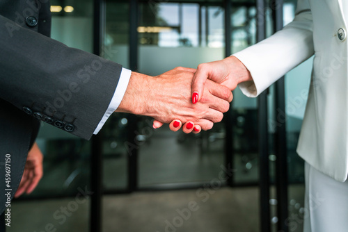 Businessman and businesswoman shaking hands in office photo