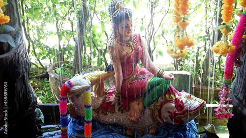 Phra Mae Thorani, goddess from Buddhist mythology, behind water of fountain. photo