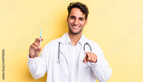 hispanic handsome man pointing at camera choosing you physician and srynge concept photo