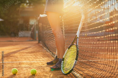 Female athlete standing by tennis racket and ball at sports court during sunny day