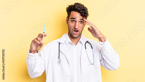 hispanic handsome man looking happy, astonished and surprised physician and srynge concept photo