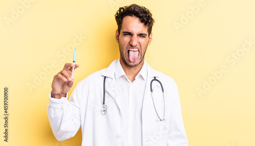 hispanic handsome man with cheerful and rebellious attitude, joking and sticking tongue out physician and srynge concept photo