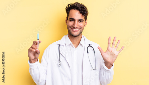 hispanic handsome man smiling and looking friendly, showing number five physician and srynge concept photo