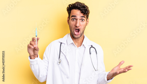 hispanic handsome man amazed, shocked and astonished with an unbelievable surprise physician and srynge concept photo