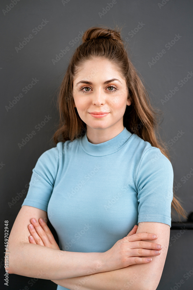 Smiling young woman with arms crossed against black background Smiling young woman with arms crossed against black background