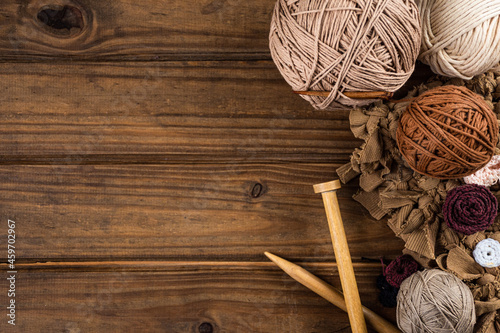 Tejidos de lana sobre mesa de madera con madejas y ovillos de lana con instrumentos para tejer