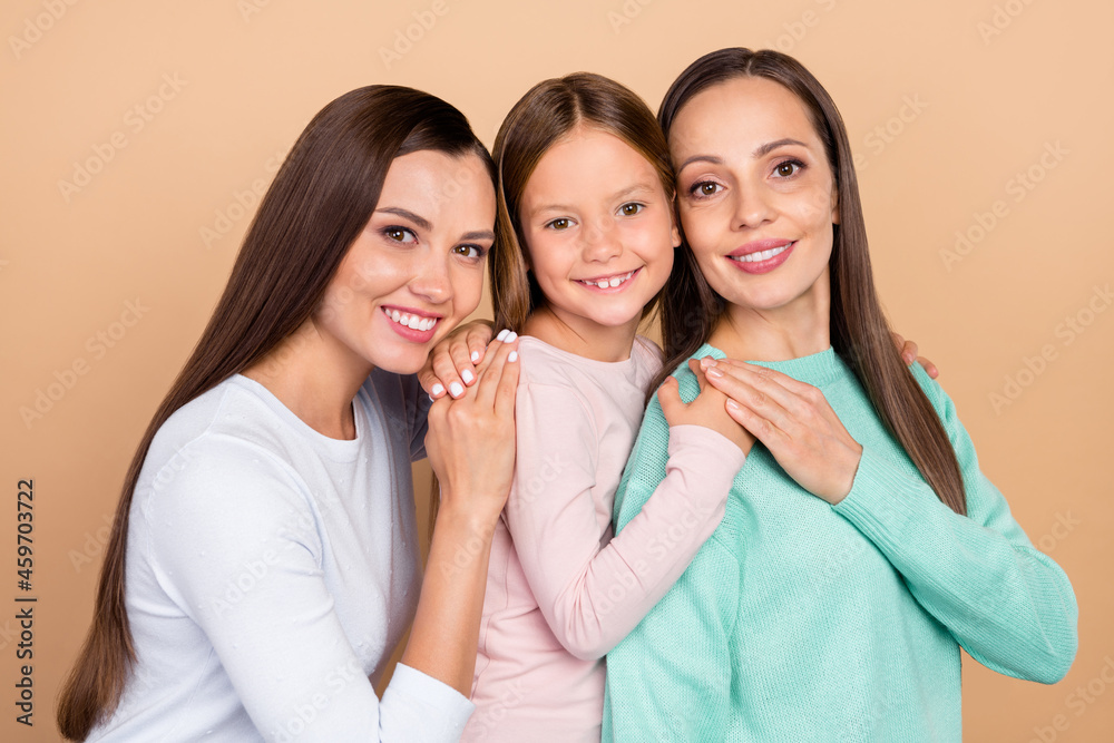 Portrait of three attractive cheerful careful brown-haired girls hugging isolated over beige pastel color background Portrait of three attractive cheerful careful brown-haired girls hugging isolated over beige pastel color background