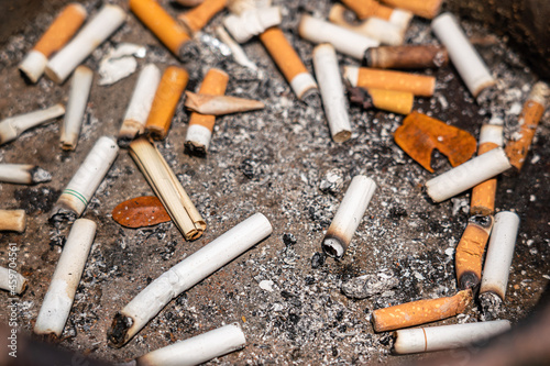 Group of cigarettes butt junk in ashtray, unhealthy concept seen. Close-up and selective focus at center part of the object.