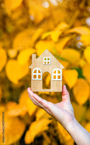 The symbol of the house in the girl's hand on the background of yellow leaves 