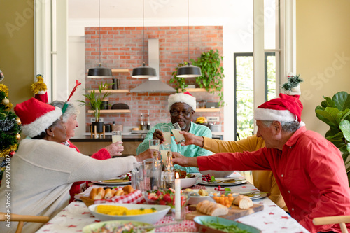 Diverse group of happy senior friends celebrating christmas together, toasting with juice