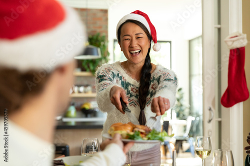 Happy asian woman in santa hat celebrating christmas with friends at home