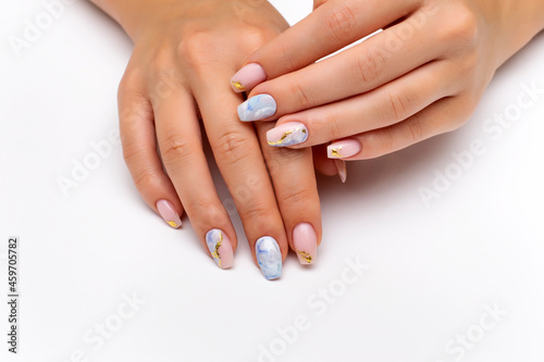 Nude, natural manicure with blue, white streaks and gold foil on long square nails. Gel nails. Heavenly manicure. Close-up on a white background.