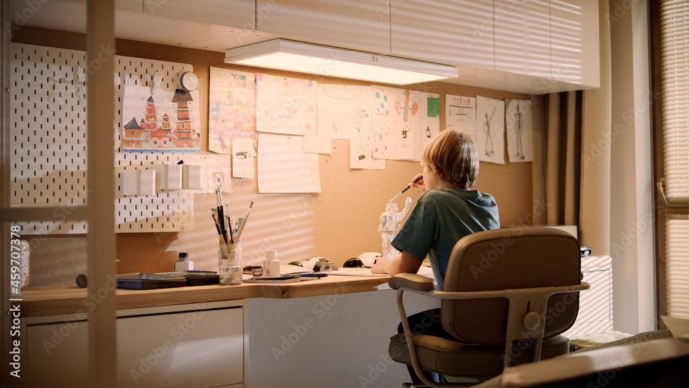 Little boy focused on work. Painting robot skeleton in his room Little boy focused on work. Painting robot skeleton in his room