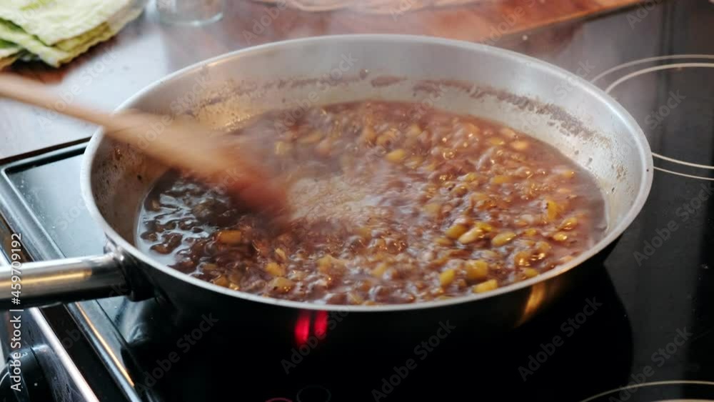 Chef hand using wooden flipper with stirring seasoning sauce in pan Chef hand using wooden flipper with stirring seasoning sauce in pan