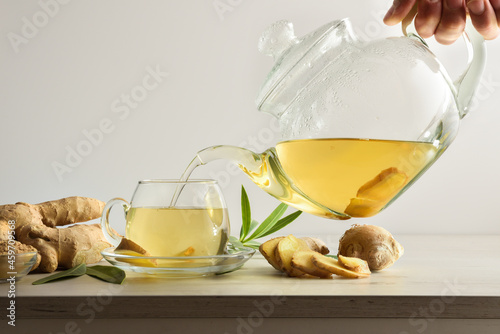 Tableau sur toile Man serving cup with ginger root infusion on bench isolated