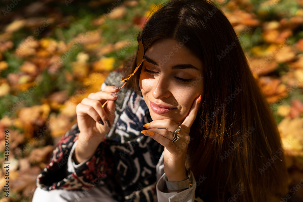 Autumn portrait of a beautiful girl with a maple leaf in her hand Autumn portrait of a beautiful girl with a maple leaf in her hand