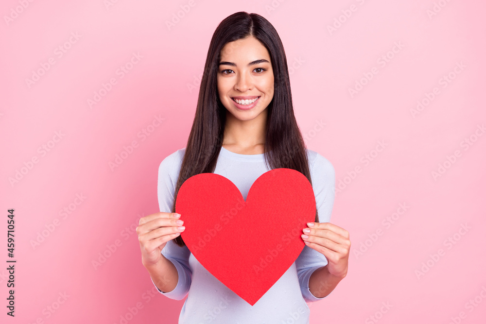Photo portrait of girl keeping red heart smiling on valentines day isolated on pastel pink color background Photo portrait of girl keeping red heart smiling on valentines day isolated on pastel pink color background