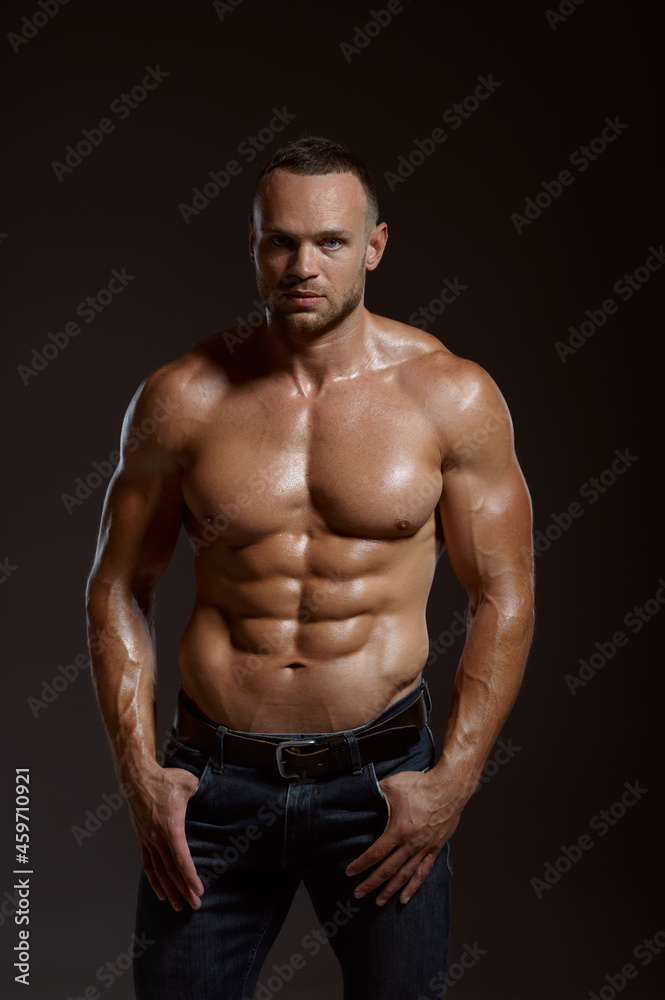 Male muscular athlete poses in studio
