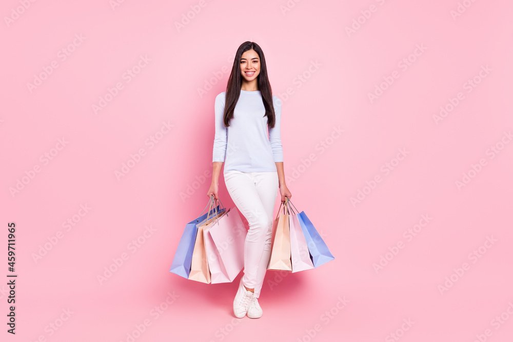 Full length body size view of attractive cheerful girl carrying bags isolated over pink pastel color background Full length body size view of attractive cheerful girl carrying bags isolated over pink pastel color background