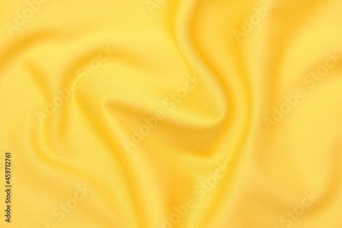 Close-up texture of natural orange or yellow fabric or cloth in same color. Fabric texture of natural cotton, silk or wool, or linen textile material. Yellow canvas background.