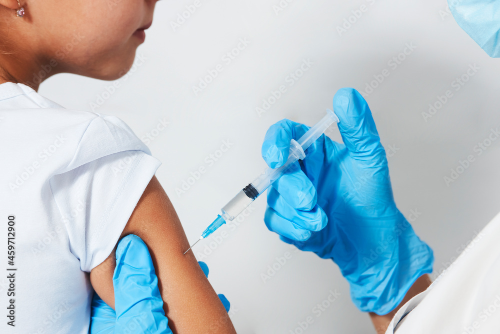 Female doctor injecting vaccine to girl Female doctor injecting vaccine to girl