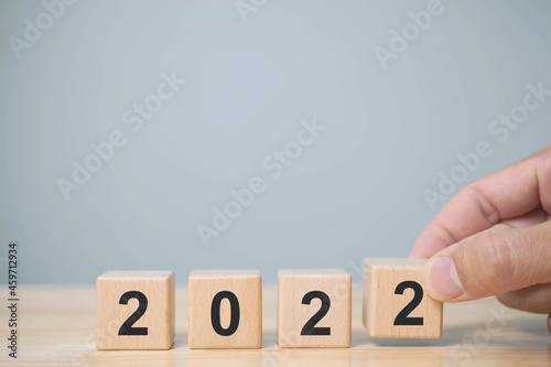 Hand of man putting wood cube 2022. New year concept.