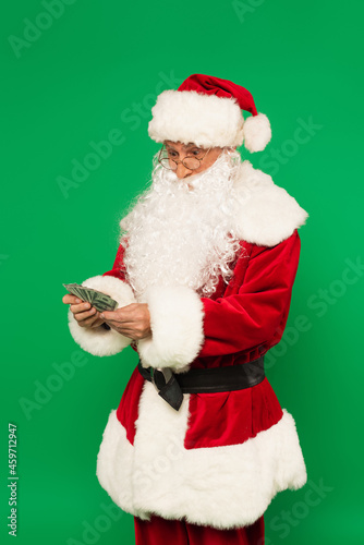 Excited santa claus holding dollars isolated on green
