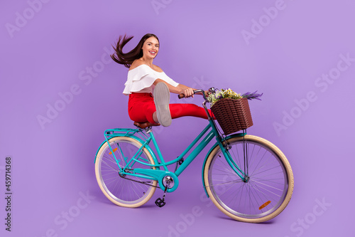 Profile photo of active lady enjoy bike ride raise legs wear white blouse trousers shoes isolated purple color background © deagreez