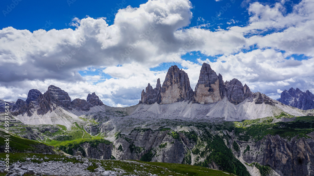 Three peaks in the Italian dolomites. Mountain panorama with clouds and blue sky. High alpine landscape with grass and stones. Landscape photography